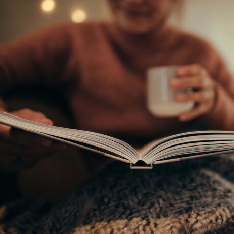 femme lisant un livre en buvant une boisson chaude