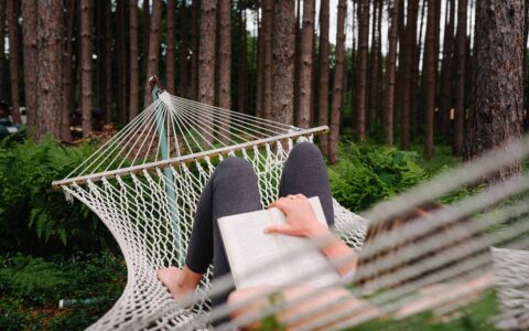 personne qui lit dans un hamac en nature