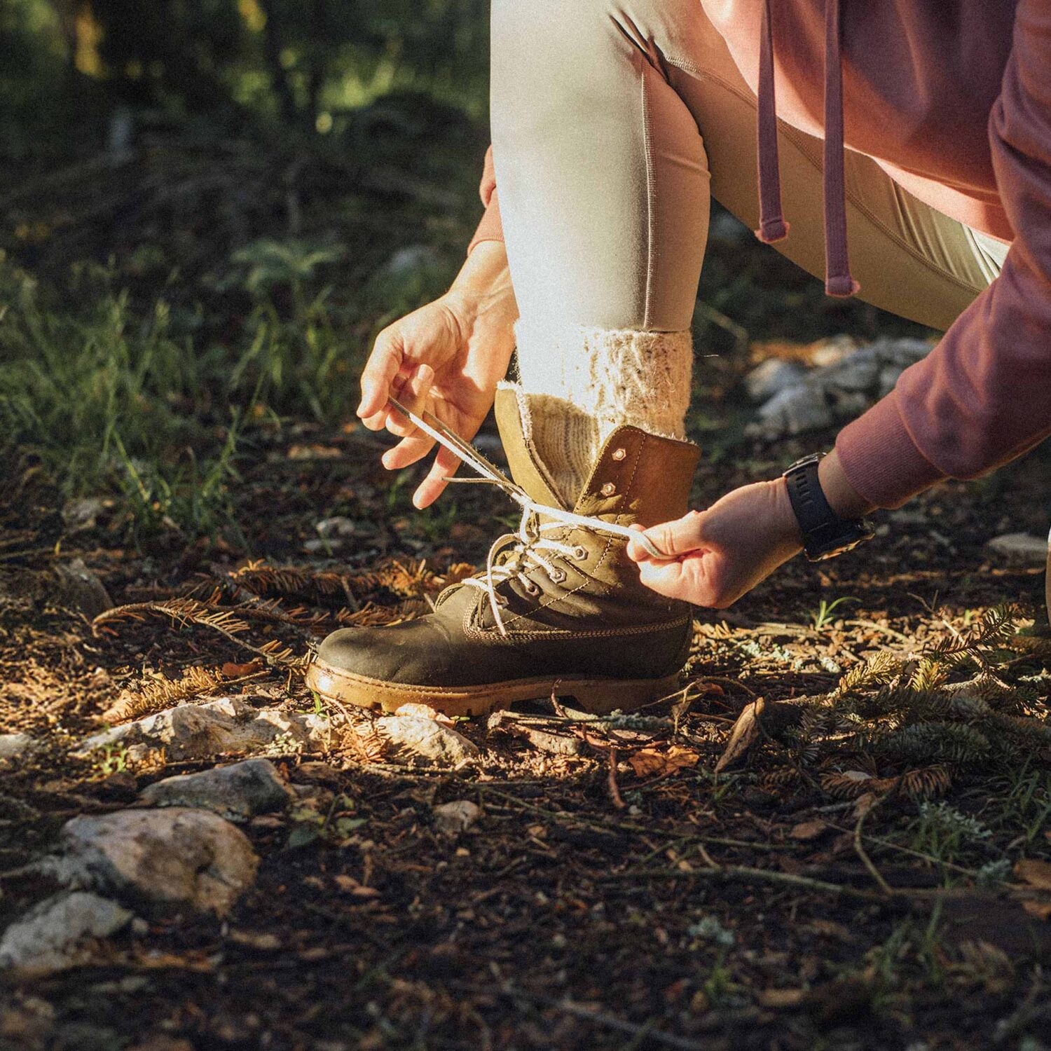 une personne qui attache sa botte de randonnée en nature