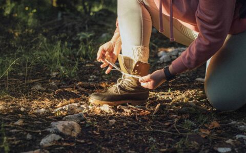 une personne qui attache sa botte de randonnée en nature