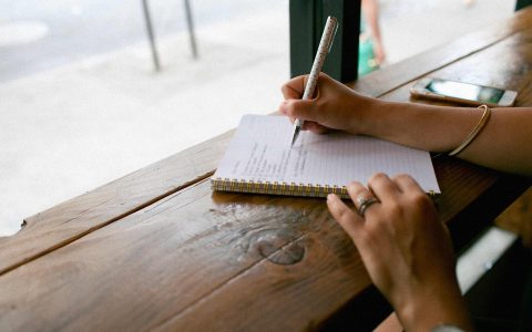 personne écrivant dans un cahier